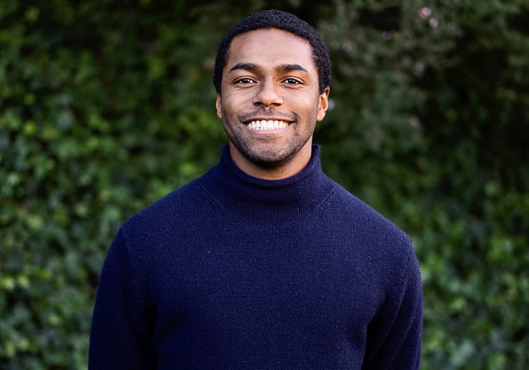 John Franklin smiles in front of a hedge of ivy
